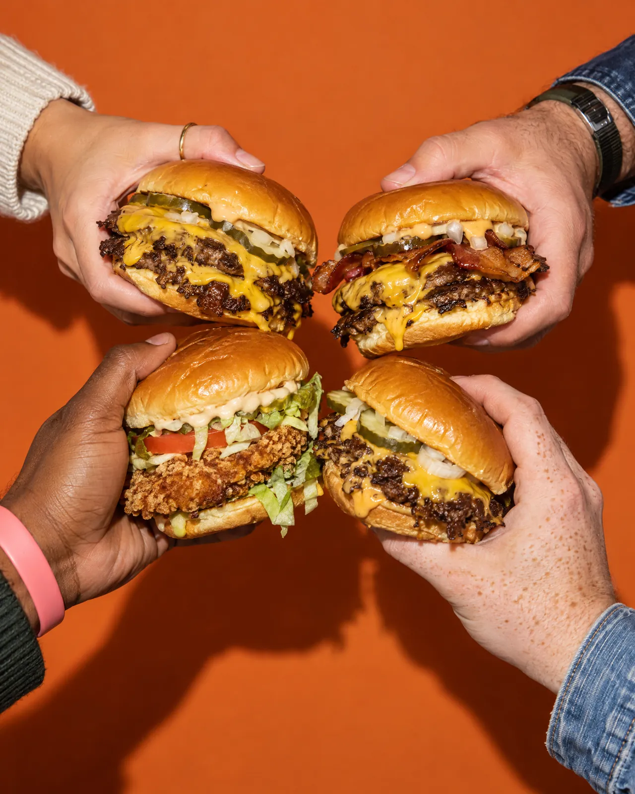 Four burgers held together on orange paper, made with AI